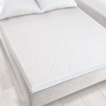 Prześcieradło żakardowe bez gumki 150x205 w kolorze białym, rozłożone na łóżku. Wzór z delikatnym, teksturowanym nadrukiem roślinnym. Widoczne poduszki na tle jasnej, drewnianej podłogi. Produkt leżący, prezentujący estetykę sypialni.