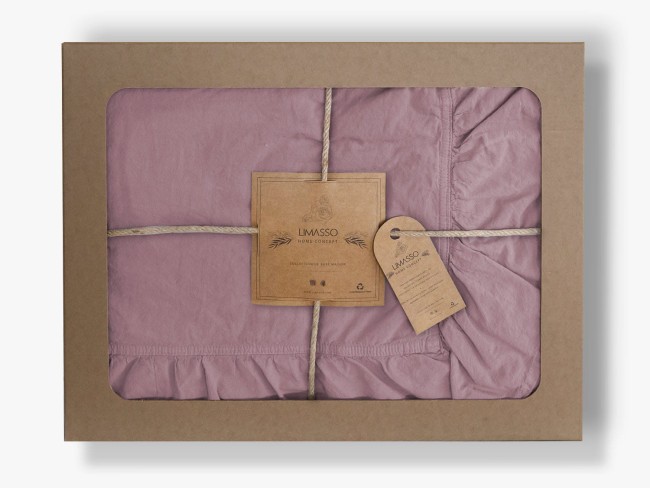 Pościel bawełniana z falbanką w odcieniu fioletowym, rozmiar 220x200 cm, zapakowana w prostokątne kartonowe opakowanie. Widoczny przewiązany sznurkiem.