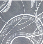 Biała firana haftowana o wysokości 280 cm, z grafitowym tłem. Zbliżenie na detal haftu przedstawiającego geometryczne wzory w postaci falistych linii, wykonanych białą nicią, dodających tekstury i elegancji.