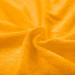 Prześcieradło frotte z gumką w kolorze żółtym, wykonane z miękkiego materiału o teksturze pętelkowej, leży na powierzchni. Idealne do łóżeczka o wymiarach 40x90 cm. Zbliżenie na fakturę materiału, ukazujące jego grubość i wygodę użytkowania.