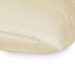 Poszewka jersey 40x40 w kolorze kremowym, leżąca na powierzchni, z widocznym zamkiem błyskawicznym. Materiał gładki, jednorodny, bez wzorów. Ujęcie z boku, ukazujące detale wykończenia. Prostokątny kształt, idealna do poduszki.