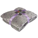 Koc mikrofibra 150x200 w kolorze antracytowym z pastelowymi kropkami. Złożony, widoczny z przodu, z widoczną wstążką w odcieniu fioletowym. Powierzchnia puszysta i teksturowana. Produkt leży na jednolitym tle.