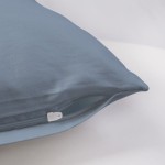 Poszewka satynowa 70x80 w kolorze błękitnym, z zamkiem błyskawicznym, leżąca na jasnym tle. Widoczna gładka faktura materiału, bez wzorów czy napisów. Ujęcie z boku podkreśla elegancki wygląd oraz detale wykończenia.