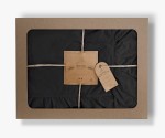 Pościel bawełniana z falbanką 220x200 Stonewashed Exclusive w kolorze czarnym, zapakowana w kartonowe opakowanie z okienkiem. Widoczne etykiety z informacjami o produkcie. Opakowanie przewiązane naturalnym sznurkiem, prezentujące elegancki styl.