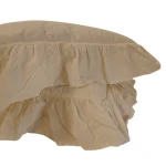 Pościel bawełniana z falbanką w kolorze beżowym, o wymiarach 220x200 cm. Ujęcie z boku, ukazuje falbany na brzegu, gładką teksturę materiału oraz luźne ułożenie. Widoczne elementy wykończenia są starannie zszyte.