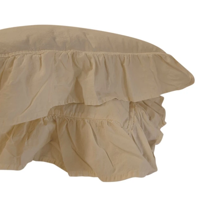 Pościel bawełniana z falbanką w kolorze beżowym, o wymiarach 220x200 cm. Ujęcie z boku, ukazuje falbany na brzegu, gładką teksturę materiału oraz luźne ułożenie. Widoczne elementy wykończenia są starannie zszyte.