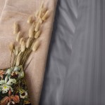 Pościel satyna bawełniana 220x200 w kolorze antracyt z delikatnym prążkiem, rozłożona na jasnym tle. W zestawie widać również beżowy koc oraz bukiet suszonych kwiatów, który podkreśla aranżację. Całość tworzy elegancki układ dekoracyjny.