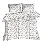 Pościel z kory 140x200 w letnie czerwone kwiaty. Ułożona na łóżku, z widocznymi poduszkami. Kolorystyka dominująca: jasno-biała z małymi, wielokolorowymi wzorami kwiatów. Materiał o teksturze kory, lekko marszczony, rozłożony.