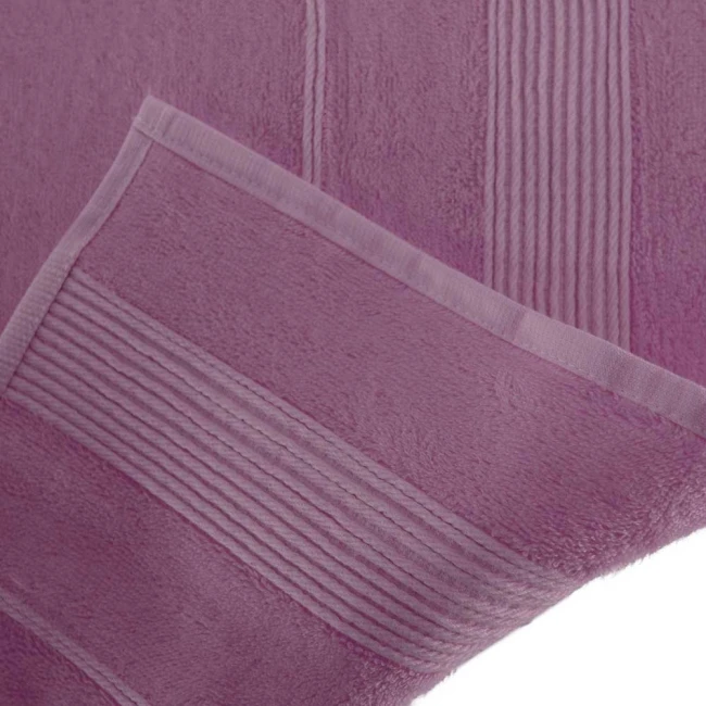 Ręcznik bambusowy w kolorze lawendowym o wymiarach 70x140 cm, ukazany z boku, złożony. Materiał jest miękki, teksturowany, z poziomymi pasami wzdłuż krawędzi. Brzeg jest wykończony delikatnym obszyciem.