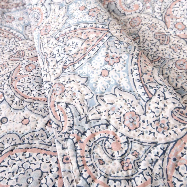 Poszewka na poduszkę 40x40 w kolorze niebieskim z pastelowym wzorem roślinnym i geometrycznym. Ułożona na płasko, z widoczną teksturą tkaniny. Dekoracje w odcieniach różu i białego, bez czytelnych napisów czy logo.