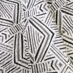 Poszewka na poduszkę 40x40 cm, wykonana z materiału w biało-czarnym wzorze geometrycznym. Ujęcie zbliżeniowe, ukazujące detale faktury tkaniny. Poszewka leży na płaskiej powierzchni, bez widocznych napisów czy logo.