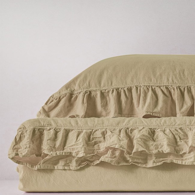 Pościel bawełniana w kolorze kremowym, z falbany na krawędzi. Rozłożona na płaskiej powierzchni, ukazuje miękką fakturę materiału oraz delikatne, zwiewne wykończenie, idealna do aranżacji sypialni. W wymiarze 220x200 cm.