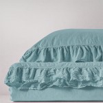 Pościel bawełniana w kolorze mineralnym niebieskim, rozmiar 220x200. Widoczna falbanka na krawędzi poszwy i poszewek, rozłożona na gładkiej powierzchni. Tło jasne, podkreślające fakturę materiału.