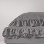 Pościel bawełniana w kolorze szarym, z falbanką, o wymiarach 220x200 cm. Materiał stonewashed, tekstura miękka i lekko zmięta. Produkt leży na jednolitym tle, ukazując detale falbany.