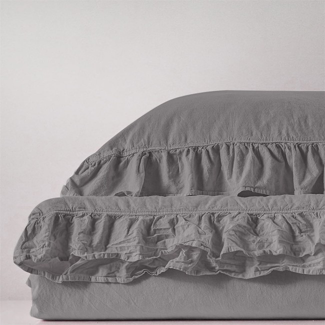 Pościel bawełniana w kolorze szarym, z falbanką, o wymiarach 220x200 cm. Materiał stonewashed, tekstura miękka i lekko zmięta. Produkt leży na jednolitym tle, ukazując detale falbany.
