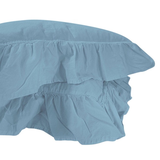 Pościel bawełniana z falbanką w kolorze niebieskim, w rozmiarze 160x200 cm. Ujęcie z boku pokazuje delikatne falbany na obrzeżu, lekko marszczony materiał, tekstura przypominająca stonewashed. Prosta kompozycja na jednolitym tle.