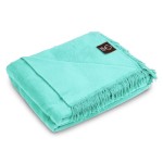 Koc bawełniany w kolorze mięty o wymiarach 150x200 cm, zwinięty w kształt prostokąta. Na brzegu widoczna frędzla. W lewym górnym rogu umieszczona czytelna metka z logo. Produkt prezentuje się na jednolitym tle.