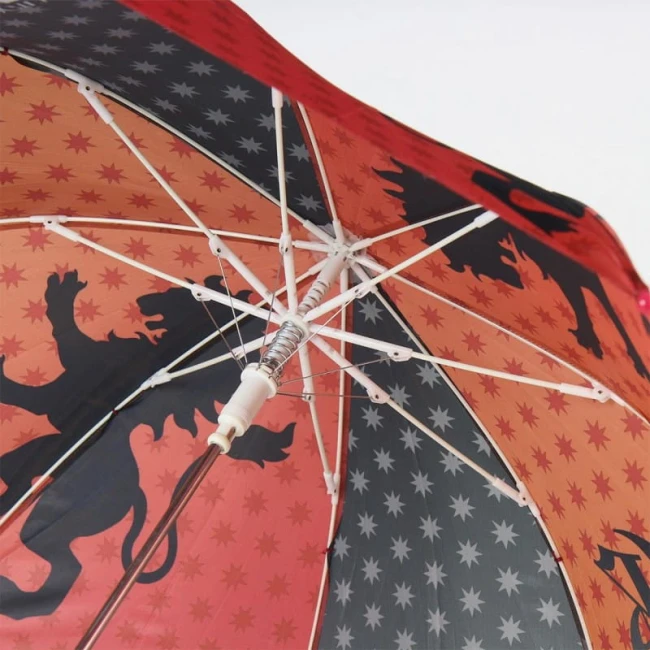 Parasol dziecięcy Harry Potter, w czerwonym kolorze, z wzorem przedstawiającym czarne lwy oraz gwiazdki. Ujęcie z dołu, ukazujące wnętrze czaszy i mechanizm otwierania. Elementy metalowe w białej obudowie oraz plastikowy uchwyt.
