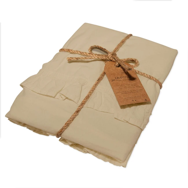Komplet poszewek bawełnianych 2x40x40 cm w kolorze kremowym, z falbanką. Złożone, przewiązane sznurkiem, z widoczną etykietą informacyjną. Tekstura materiału jest gładka, a całość prezentuje się w minimalistycznym stylu.