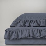 Komplet poszewek bawełnianych 2x40x40 cm w kolorze szarym, z falbanką, leżący obok siebie na jednolitym tle. Widać delikatną teksturę materiału i subtelny efekt stonewashed. Rozmiar poszewek jest wyraźnie widoczny.