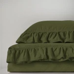 Komplet poszewek bawełnianych 2x40x40 cm w kolorze zielonym, ze stylową falbanką u dołu. Poszewki leżą obok siebie na jednolitym tle, prezentując teksturę materiału. Produkt ma subtelny, przyjemny odcień oliwkowy.