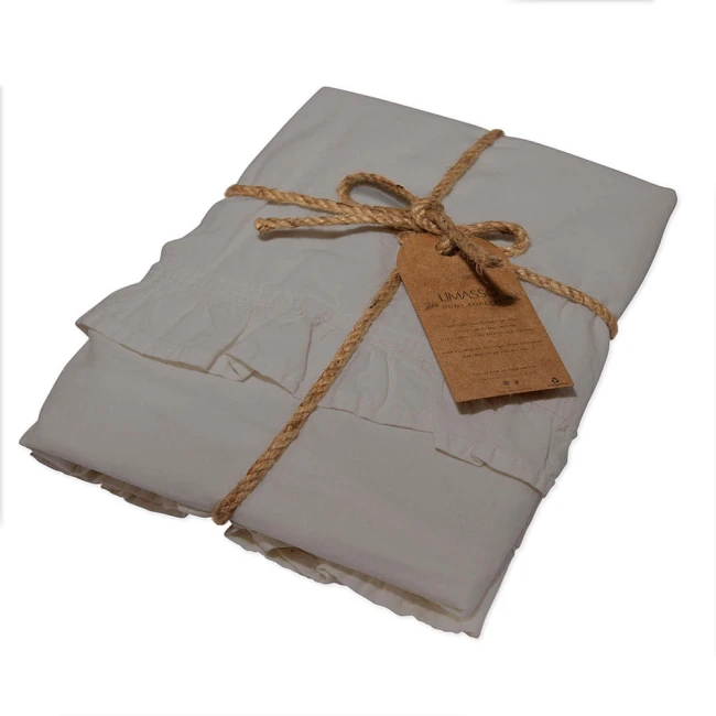 Komplet poszewek bawełnianych 40x40 cm w kolorze szaro-opalowym, z falbanką. Złożone, związane naturalnym sznurkiem, z widoczną etykietą. Tekstura materiału przypomina stonewashed, co nadaje im subtelny, vintage''owy wygląd.