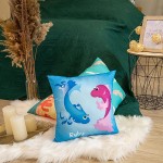 Poduszka przytulanka Ryby 40x40 w błękitnym kolorze. Z przodu widoczne kolorowe ryby: niebieska i różowa z uśmiechami. Produkt leży na miękkim, białym dywaniku w aranżacji wnętrza z ciemnozielonym tłem oraz innymi poduszkami.