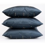 Poszewka dekoracyjna 40x40 w granatowym kolorze z złotymi wzorami, ułożona w stosie. Materiał satynowy, matowy, z widocznymi geometrycznymi kształtami, takimi jak linie i gwiazdki. Produkt leży na białym tle.