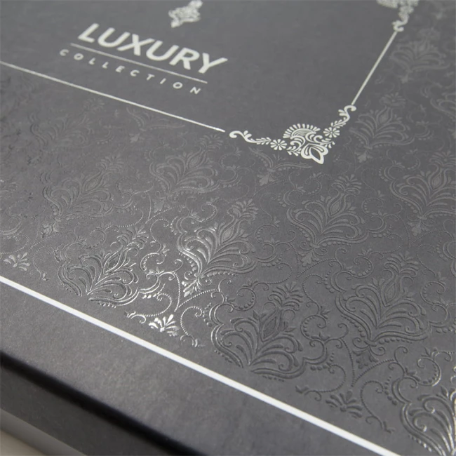 Eleganckie opakowanie pościeli z satyny bawełnianej, w odcieniu ciemnoszarym. Na wieczku widoczny napis LUXURY COLLECTION oraz delikatny żakardowy wzór z lekkim połyskiem. Opakowanie zamknięte, pokazujące gładkie, teksturowane powierzchnie.