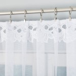 Firana gotowa Bastia żakardowa biała 500x160, z delikatnym, koronkowym wykończeniem. Ujęcie z przodu, wisząca na metalowej karnisze, z widocznymi żabkami. Tło jednolite, co podkreśla jej fakturę i lekkość.