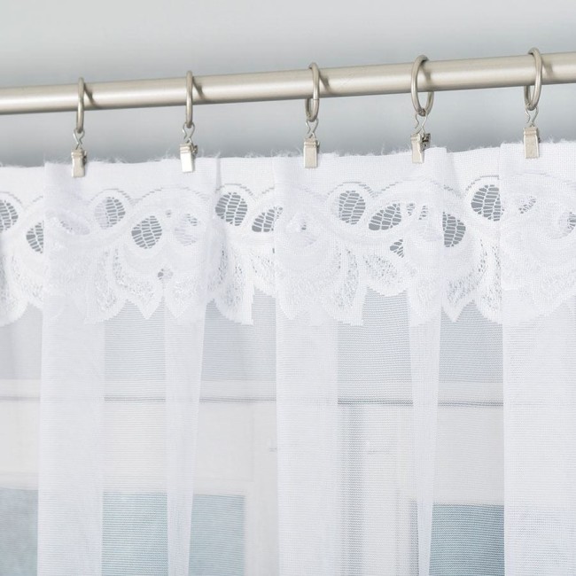 Firana gotowa Bastia żakardowa biała 500x160, z delikatnym, koronkowym wykończeniem. Ujęcie z przodu, wisząca na metalowej karnisze, z widocznymi żabkami. Tło jednolite, co podkreśla jej fakturę i lekkość.