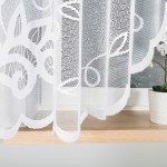 Biała firana gotowa Ewelina wykonana z żakardowego materiału o kwiatowym wzorze, wisi frontalnie na oknie. Obrzeża posiadają falbany. W tle widoczna doniczka z rośliną. Produkt ma wymiary 300x160 cm.