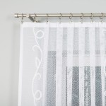 Firana żakardowa w kolorze białym, o wymiarach 300x160 cm, w delikatny wzór z motywem roślinnym. Zawieszona na metalowej karniszu, widoczna z bliska, ukazująca teksturę tkaniny. Tło jasne, neutralne, co podkreśla elegancję firany.