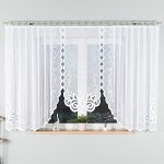 Firana gotowa Ewelina żakardowa biała o wymiarach 400x160 cm, zawieszona na karniszu. Tkanina z delikatnym, białym nadrukiem roślinnym i falistym wykończeniem. Wisząca na oknie, w tle widoczny ciemny krajobraz oraz rośliny na parapecie.