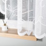 Firana gotowa Ewelina żakardowa biała 400x160, zwiewna, z delikatnym wzorem. Ujęcie z boku, zawieszona w oknie, naprężona. Tło minimalistyczne, drewniana półka z białą dekoracją. Produkt o przezroczystej strukturze, elegancko zdobi wnętrze.