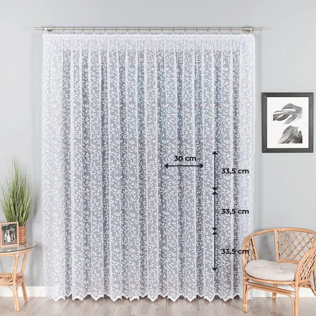 Firana żakardowa Zuzanna w kolorze białym, o wysokości 250 cm, z delikatnym wzorem roślinnym. Wiszący materiał z teksturą, z detalami wymiarów: szerokość 30 cm, wysokość 33,5 cm. Tło w neutralnym kolorze, z naturalnymi elementami wnętrza.