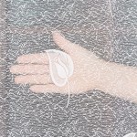 Firana żakardowa w białym kolorze z delikatnym wzorem, o wysokości 250 cm, zawieszona w poziomie. Widoczna ręka trzymająca fragment firany, eksponując szczegóły tekstury i wzoru. Tło jasne, co podkreśla jasny odcień materiału.