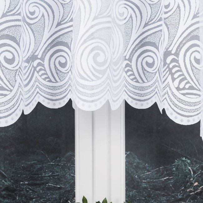 Firana żakardowa w kolorze białym o wymiarach 300x160 cm, z delikatnym wzorem w formie falistych linii i spiralnych motywów. Ujęcie frontalne, wisząca na oknie, z lekko falującym dołem. Tło ciemne, naturalne, co podkreśla jasność firany.