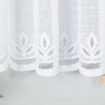 Firana gotowa Pola żakardowa w kolorze białym, o wymiarach 500x160 cm. Wzór z delikatnymi liśćmi na dolnej krawędzi. Produkt wiszący, wykonany z tekstylnego materiału o ażurowej fakturze, idealny do wypełnienia okna w jasnym wnętrzu.