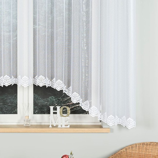 Firana żakardowa w kolorze białym o wymiarach 400x160 cm, zawieszona na oknie. Delikatny wzór z falbaniastym wykończeniem widoczny na dolnej krawędzi. Produkt idealny do aranżacji wnętrz, tworzy efekt lekkości i elegancji.