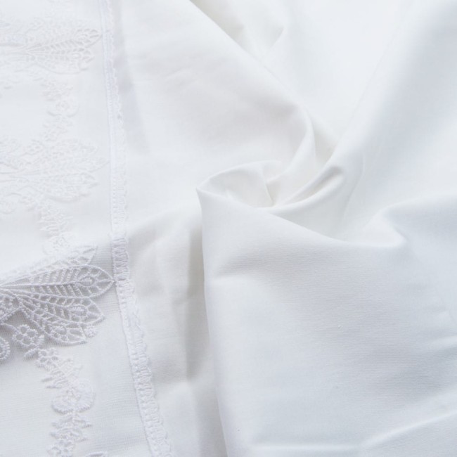 Pościel z gipiurą 160x200 w kolorze białym, wykonana z bawełnianej satyny, leżąca na gładkiej powierzchni. Widoczny detal koronkowej dekoracji wzdłuż brzegu. Faldy tkaniny ukazują gładką fakturę materiału.