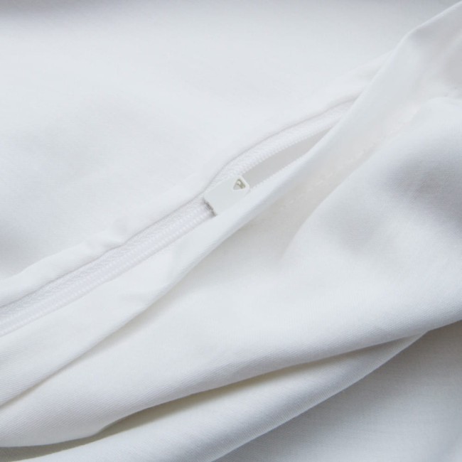 Zbliżenie na zamek błyskawiczny białej pościeli satynowej z gipiurą, rozłożonej na gładkiej powierzchni. Widoczne detale tkaniny oraz struktura materiału, ukazujące jego miękkość i gładkość. Brak dodatkowych dekoracji.