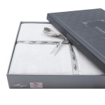 Pościel satyna bawełniana z gipiurą w kolorze białym, rozmiar 220x200, zapakowana w eleganckie pudełko z szarym wiekiem i wstążką. Widać delikatny wzór gipiury. Logo Darymex widoczne na opakowaniu. Produkt leżący na białym tle.