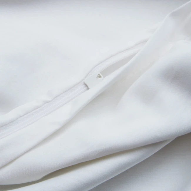 Biała pościel z gipiurą w rozmiarze 220x200 cm, wykonana z satyny bawełnianej. Widoczne zamknięcie na zamek błyskawiczny, gładka faktura materiału, leżąca na gładkim tle. Detal zamka i szwy w kolorze białym.