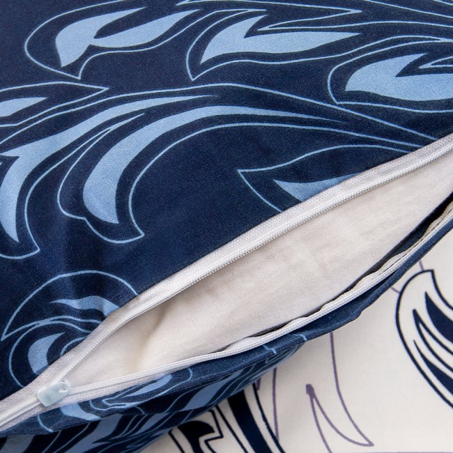 Zbliżenie na pościel w kolorze granatowym z niebieskimi wzorami, z zamkiem błyskawicznym. Widoczna dolna część poszwy na poduszkę z jasnej mikrowłókniny, ułożona na białym tle. Detal ukazuje teksturę materiału oraz zamknięcie.