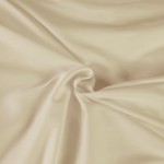 Pościel satyna bawełniana 140x200 w kolorze kremowym, z gładką, matową fakturą. Widok z góry, produkt leżący, złożony w kształcie spirali. Optymalna do aranżacji sypialni, na jednolitym tle. Idealny wybór dla osób ceniących komfortowy sen.