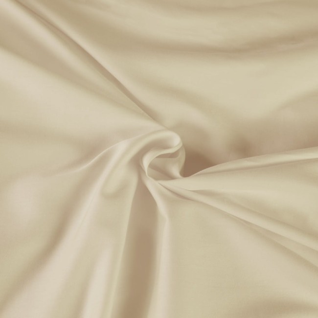 Pościel satyna bawełniana 140x200 w kolorze kremowym, z gładką, matową fakturą. Widok z góry, produkt leżący, złożony w kształcie spirali. Optymalna do aranżacji sypialni, na jednolitym tle. Idealny wybór dla osób ceniących komfortowy sen.