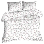 Pościel z kory 160x200 w kolorze białym z drobnym wzorem różowych kwiatuszków. Złożona, z poduszkami ułożonymi frontalnie. Wykonana z teksturowanego materiału, idealna do sypialni. Tło białe, podkreślające delikatny wzór.