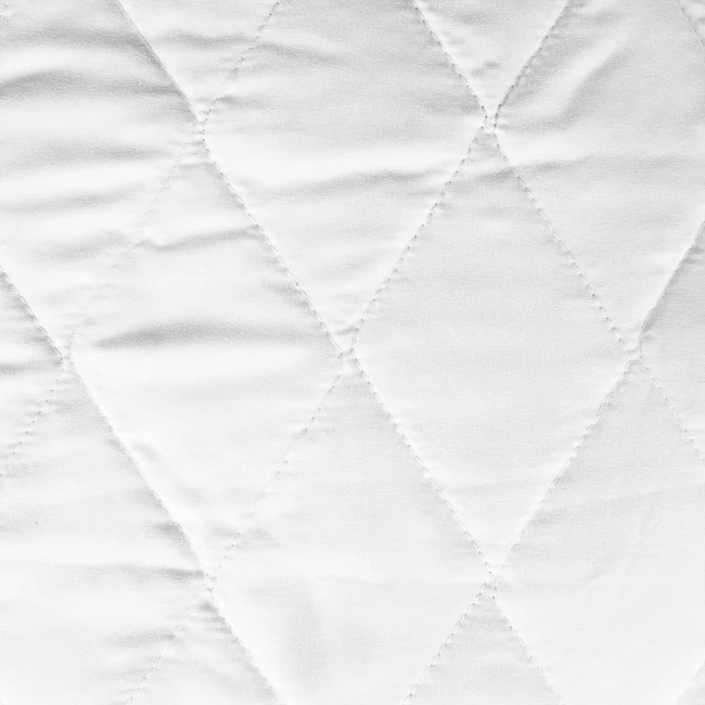 Biała poduszka antyalergiczna 50x70 klasyczny model, pikowana, z wyraźnym wzorem rombów. Wykonana z gładkiego materiału, z delikatnie błyszczącą powierzchnią. Zbliżenie na teksturę tkaniny, widoczny równomierny szew. Idealna do użytku domowego.