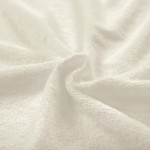 Pościel frotte 160x200 w kolorze ecru o miękkiej, teksturowanej powierzchni. Zdjęcie przedstawia materiał w zbliżeniu, ukazując jego subtelne fałdy oraz gładką fakturę. Produkt leży na płaskiej powierzchni.